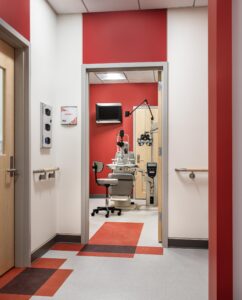 Colored floor tiles and painted soffits mark exam room entrances. Color continues inside with floor strips and accent walls.