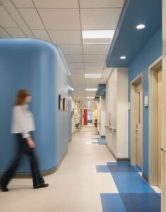The north-south corridor offers a clear line of sight. Curved Pod rooms and color accents break up the linear space and aid wayfinding.